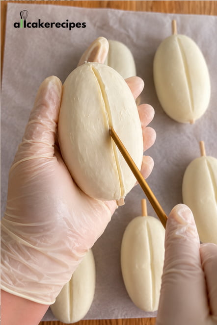 Creating a coffee bean groove in a mascarpone-coated tiramisu dessert using a thin tool.